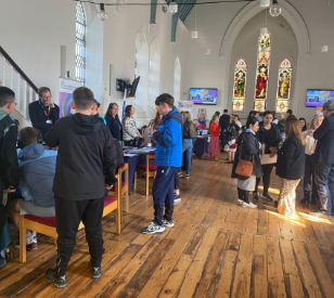 Groups of students and mature students standing chatting in group attending education fair in church