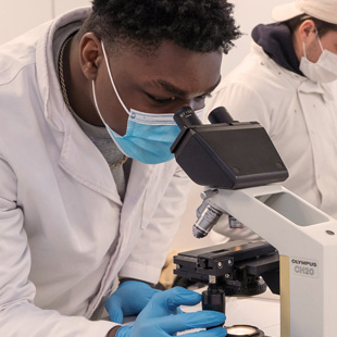 science student in lab looking through microscope