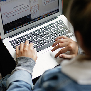 student typing on laptop
