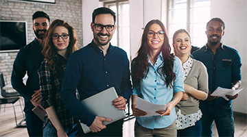 Smiling employees carrying laptops and notes