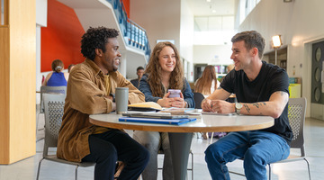 3 students sitting at round table in campus